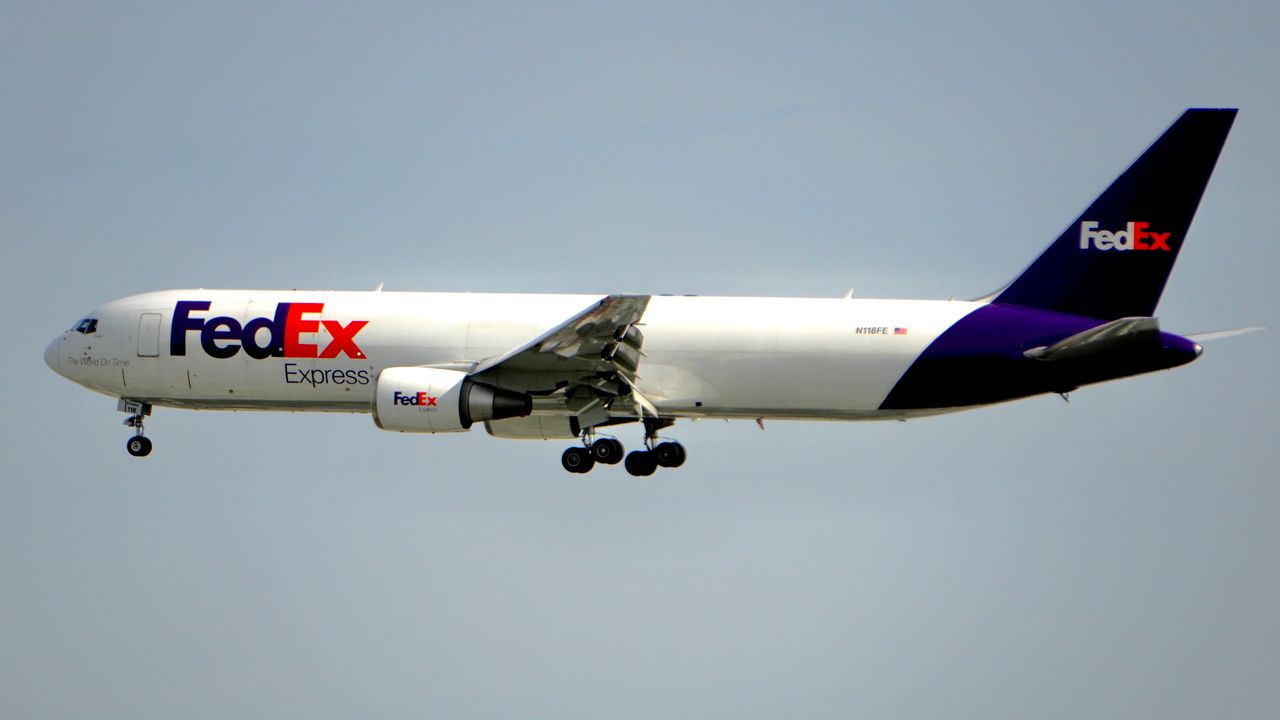 A FedEx cargo plane captured in mid-flight against a clear blue sky, showcasing air logistics.