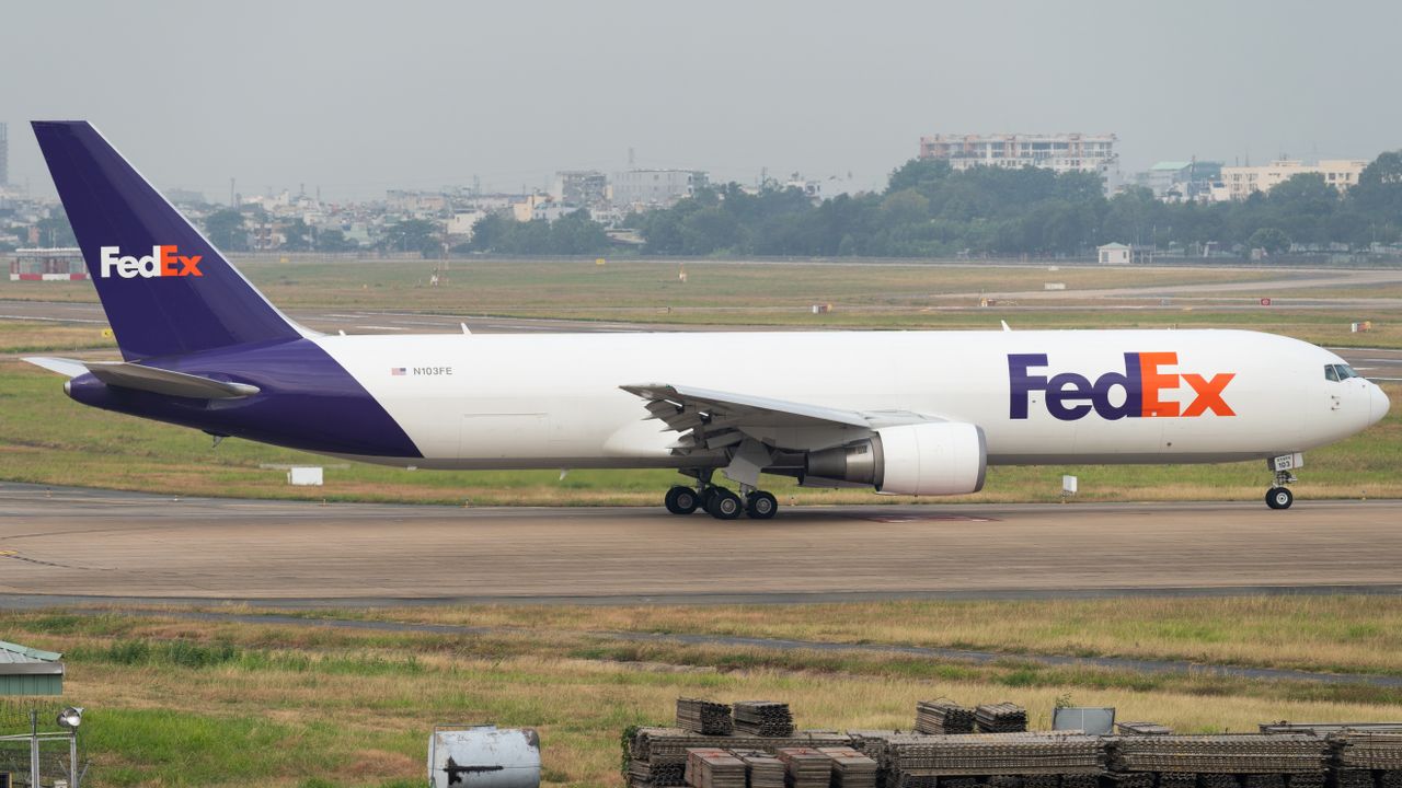 FedEx cargo airplane on runway, ready for takeoff at an international airport.